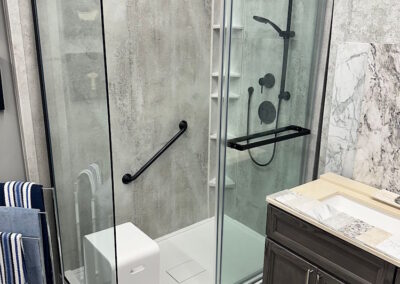 In the Peterborough Bath Renovators Show room, a custom glass sliding door, with black shower fixtures, as well as a series of colour options available for the custom bathroom.