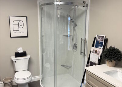 In the show room a custom round cornered shower with clear glass doors with a sink next to it.
