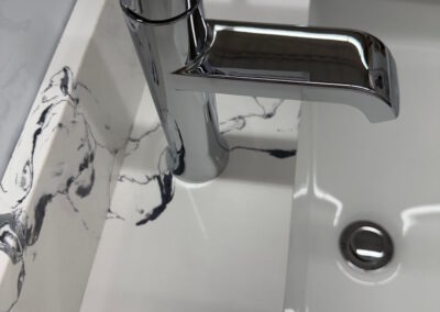 A close up view of the white and black marbling, along with a shiny silver faucet from Peterborough Bath Renovators Show Room.